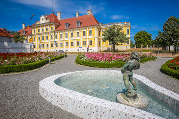 View of a water fountain with statue and flowers in a park with the City museum located in the Eltz castle in the background  in Vukovar, Croatia.