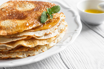Traditional breakfast pancakes with butter on a plate on a white wooden table close-up