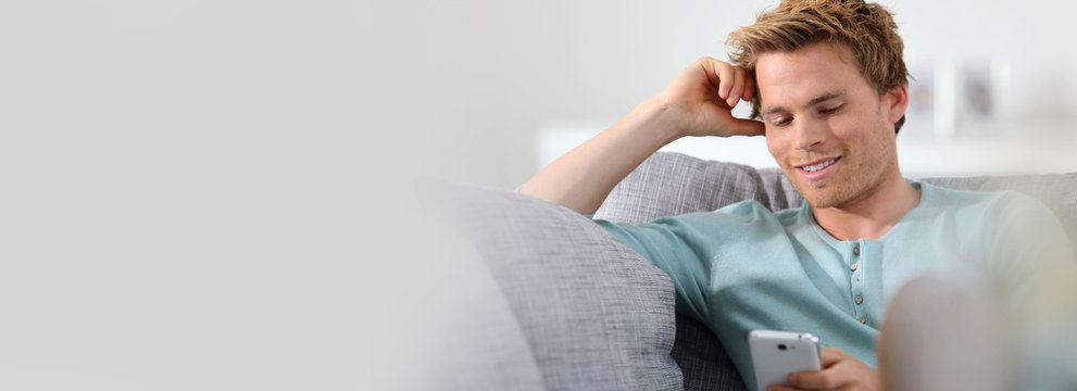 Young man in sofa with smartphone, template