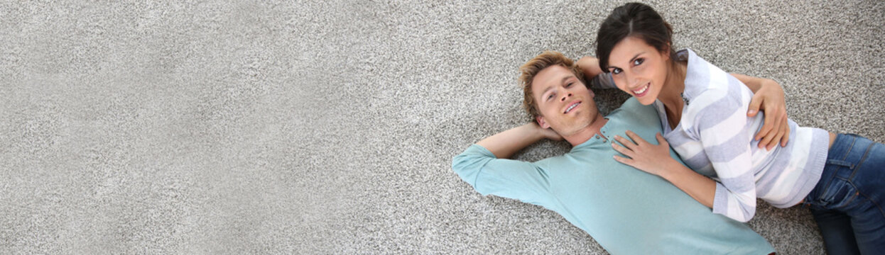 Cheerful young couple laying on carpet floor, template