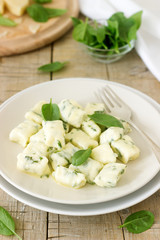 Homemade gnocchi with ricotta, cheese and spinach on a light plate.
