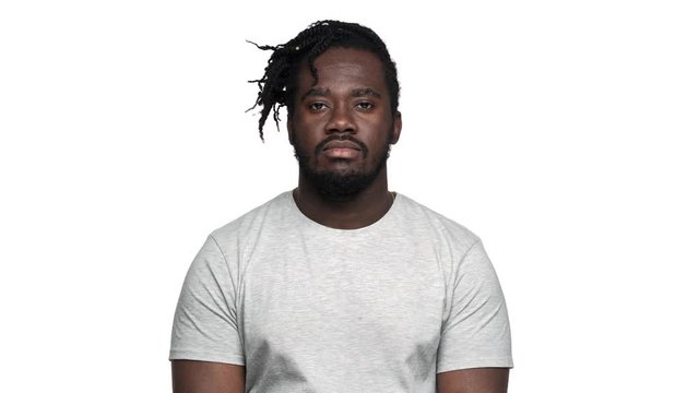 Portrait of disinterested displeased dark skinned guy in casual t-shirt with afro pigtails rolling his eyes in irritation or boredom, isolated over white background. Concept of emotions