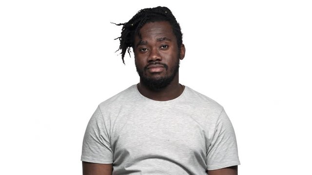 Portrait of uncaring african american man in casual t-shirt with afro pigtails throwing hands aside and shrugging don't know or can't help, isolated over white background. Concept of emotions