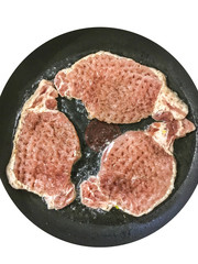 Pieces of meat in a frying pan on white isolated background. Steak, escalope, pork
