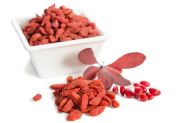 Branch of ripe red barberries and dried goji berries isolated on white background