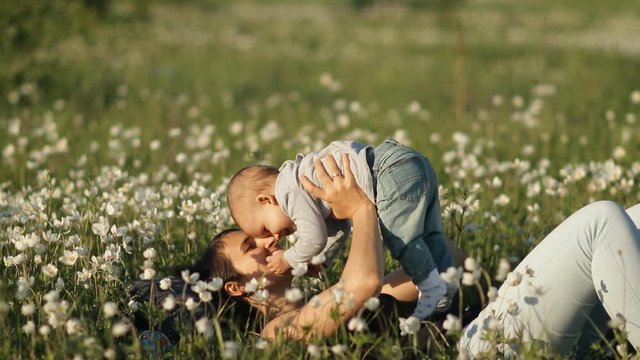 Slow motion of a young happy mother and child in a flower field at sunset.
