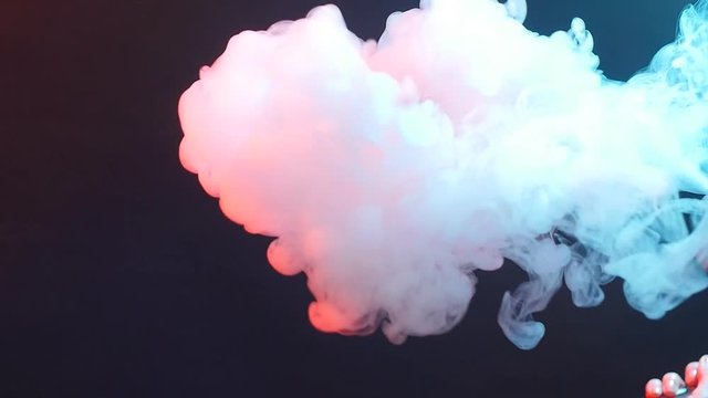 Young woman smokes electronic cigarette in color light. Night life and vape concept
