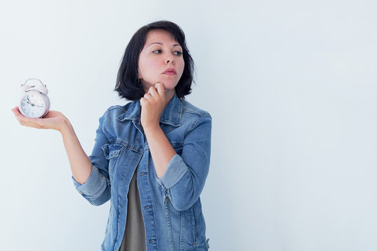 Asian woman holding a pink alarm clock on a white background. the concept of time management. get control of your life