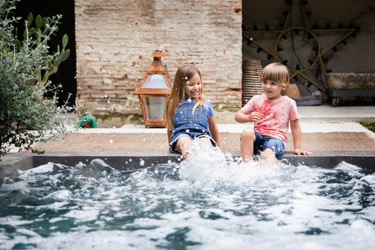 Siblings splashing on the edge of a pool