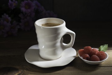 Cup of coffee with raspberries bowl