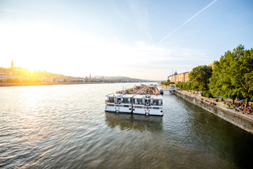 Fototapeta premium Landscape view on Danube river with tourist ship during the sunset in Budapest city, Hungary
