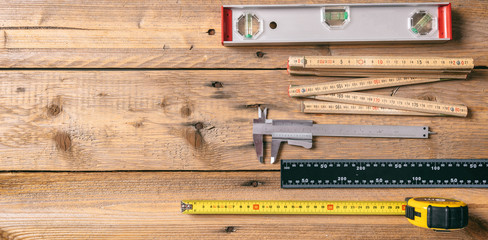 Carpentry. Measure tape, spirit level and rulers on wooden background, copy space, top view