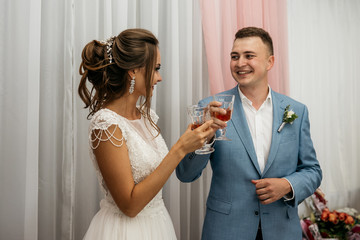 The bride and groom clink glasses and laugh