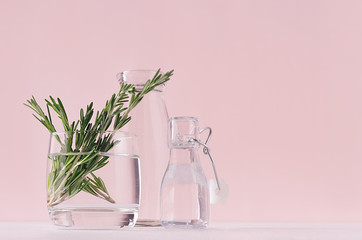 Gentle spring vanilla background of fresh bouquet rosemary in glass and retro bottles on white...