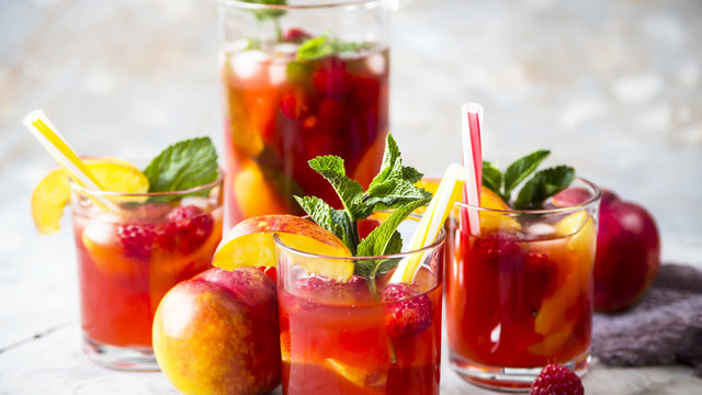 Light summer refreshing drink with fruits and berries - sangria. In glasses on a gray table