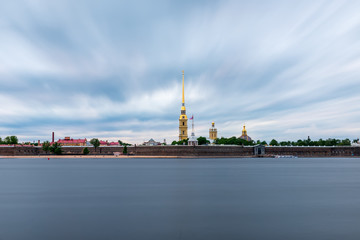 St Petersburg, Russia. Peter and Paul fortress with the Palace promenade, Petropavlovskaya krepost, white nights.Blue cloudy sky, dark water of the Neva river