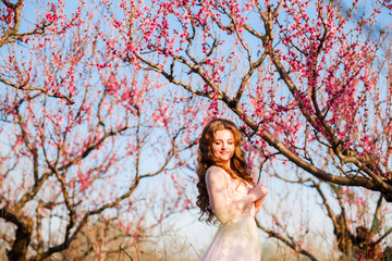 A girl in a beautiful dress strolls through a flowering garden