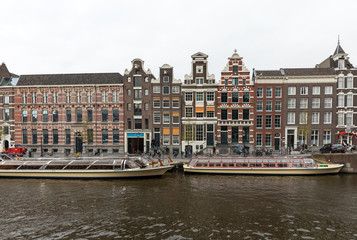 Naklejka premium View on Rokin Canal, Oude Turfmarkt street and Tourboats ready for canal cruises in Amsterdam, Holland, Netherlands.