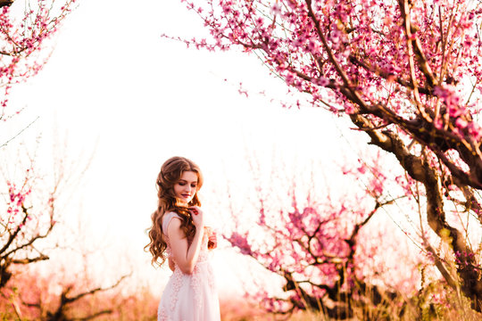 A girl in a beautiful dress strolls through a flowering garden