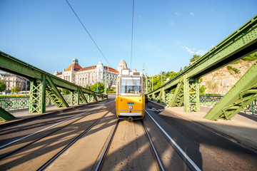 Plakat View on the famous Liberty bridge with old yellow tram during the morning light in Budapest, Hungary