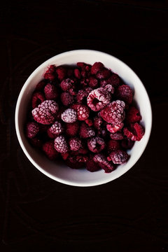 Frozen raspberries on a white bowl