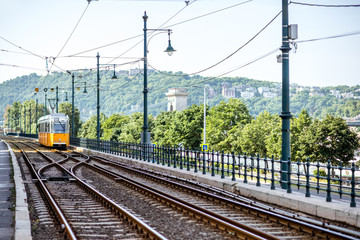 Fototapeta premium Railway with old yellow tram near the river during the morning light in Budapest city, Hungary