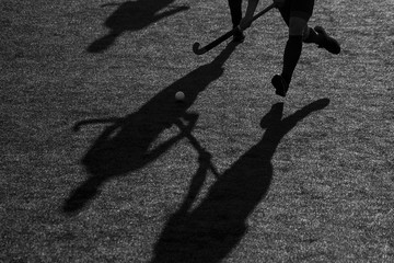 Silhouette. The shadow of a hockey player is running with a hockey stick on a hockey field.