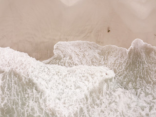 Small figures in the waves on a beach