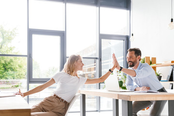 Obraz premium Couple of happy colleagues giving high five