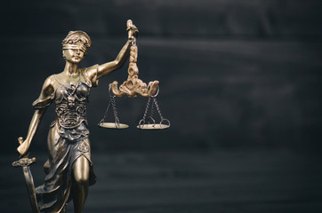 Scales of Justice, Justitia, Lady Justice on a black wooden background.
