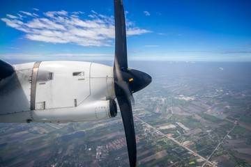 Naklejka na ściany i meble Propeller and engine of vintage airplane, seen through an airplane window from the passenger seat.
