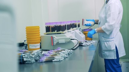 A nurse scans barcodes on blood samples bottles, then places them onto a special rack. - Powered by Adobe