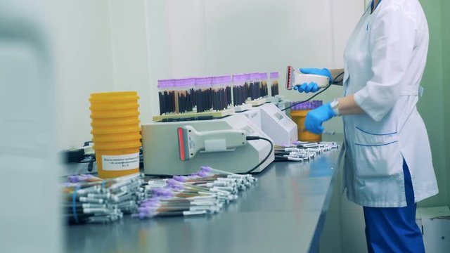 A nurse scans barcodes on blood samples bottles, then places them onto a special rack.