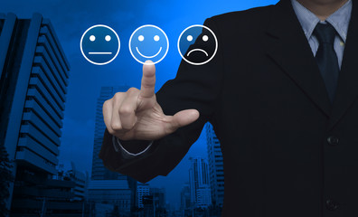 Businessman pressing excellent smiley face rating icon over modern office city tower, Business customer service evaluation and feedback rating concept