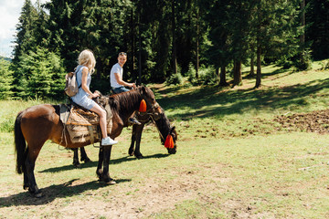 beautiful couple riding on horses in the mountains