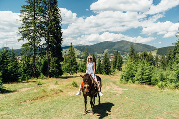 lovely girl riding a horse in the mountains