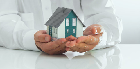Business man is holding a house