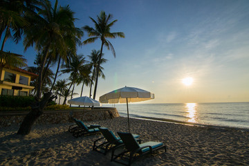 Beach loungers on the deserted coast sea at sunrise.