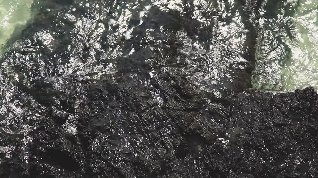 Wave of Sea Water Attack to Rough Black Rock Surface  