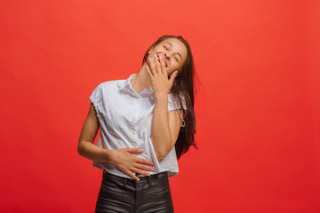 The happy business woman standing and smiling against red background.