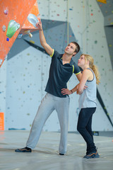 fit couple at the rock climbing wall at the gym