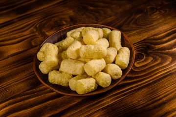 Ceramic plate with corn sticks on wooden table