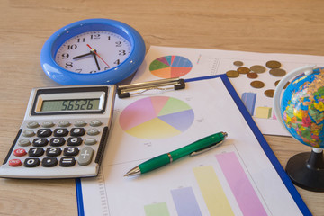 charts and graphs, collage with clock. Clock, calculator, pen, graphics, small change on table. Businesses concept