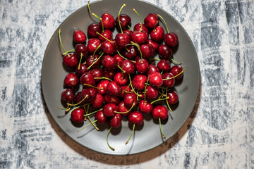 Dark, ripe and juicy cherries on a black plate
