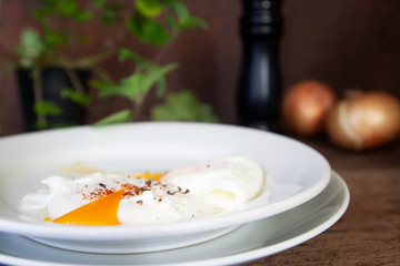 Healthy breakfast, poached eggs on white plate with food ingredient on wooden table