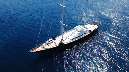 Fototapeta premium Aerial drone bird's eye view photo of wooden deck luxury sail boat docked in mediterreanean deep blue waters