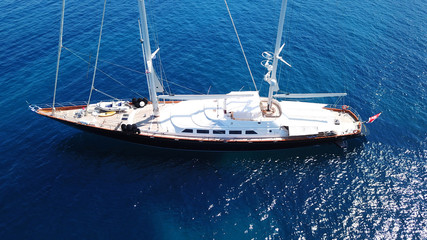 Aerial drone bird's eye view photo of wooden deck luxury sail boat docked in mediterreanean deep blue waters