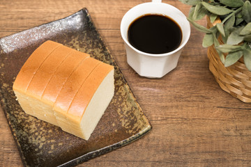 Homemade plain butter cake soft and moist. Slice of butter cake on plate and serve with black coffee on wooden background