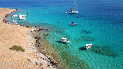 Fototapeta na wymiar Aerial drone bird's eye view photo from boats docked in turquoise clear water rocky beach in island of Irakleia, Cyclades, Greece