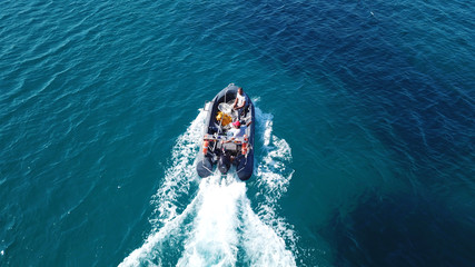 Aerial bird's eye view of inflatable rib boat cruising in high speed in turquoise clear water sea
